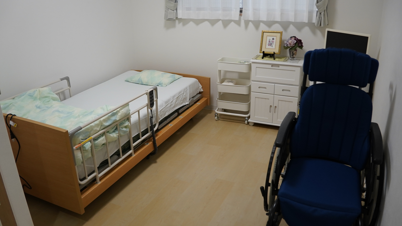 ナーシングホームかんなの居室。介護用ベッドと車いす、収納家具が置かれた個室